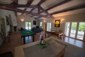 Un salón amplio con mesa de billar, comedor y chimenea.