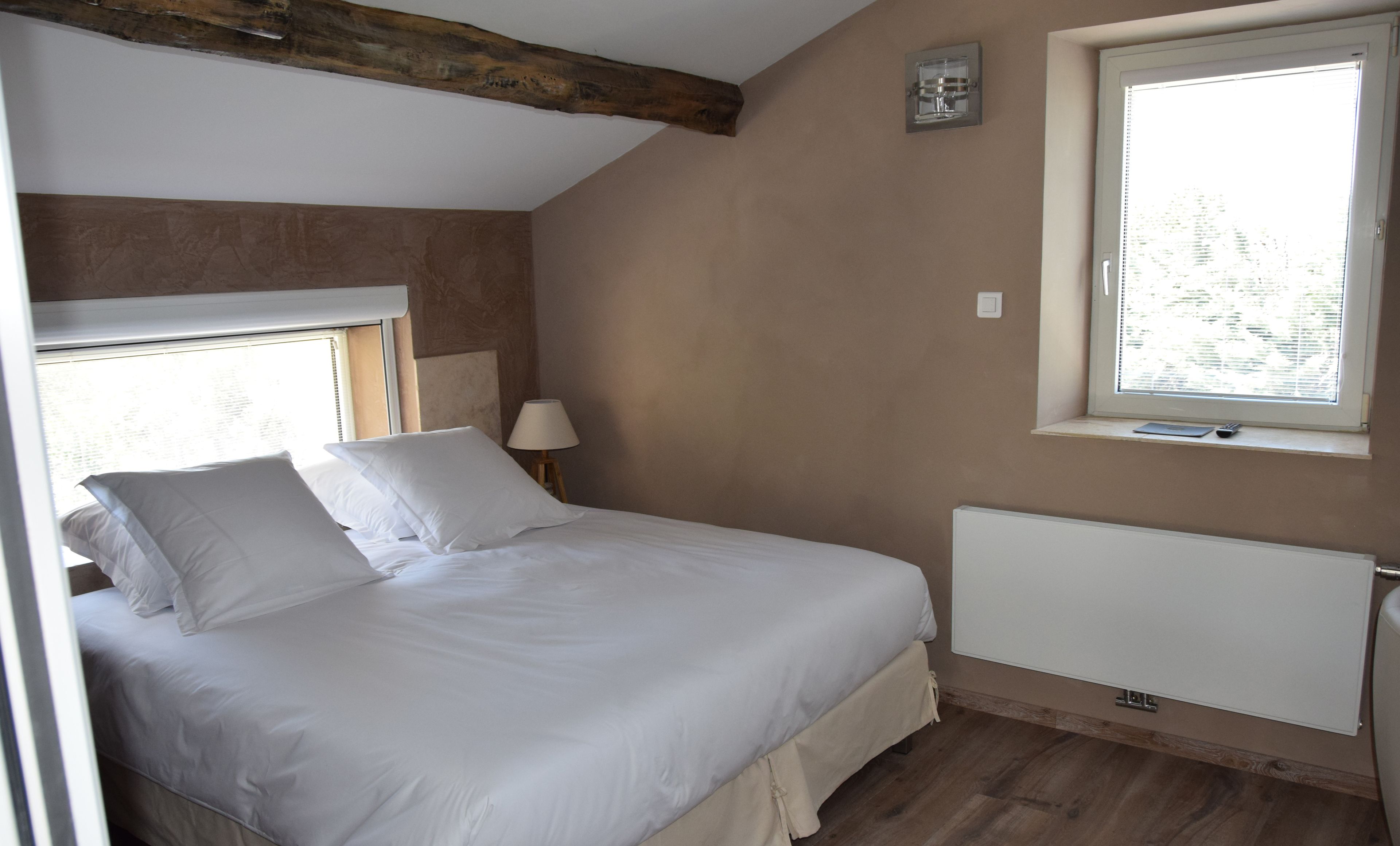 A bedroom with a bed, a window, a lamp, and a radiator.