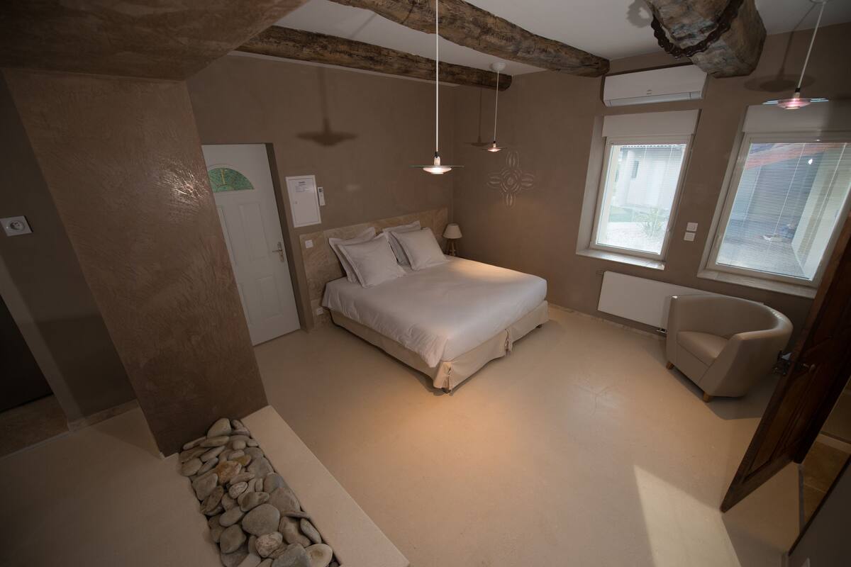 Ein Schlafzimmer mit einem Bett, einem Sessel und einem Fenster.