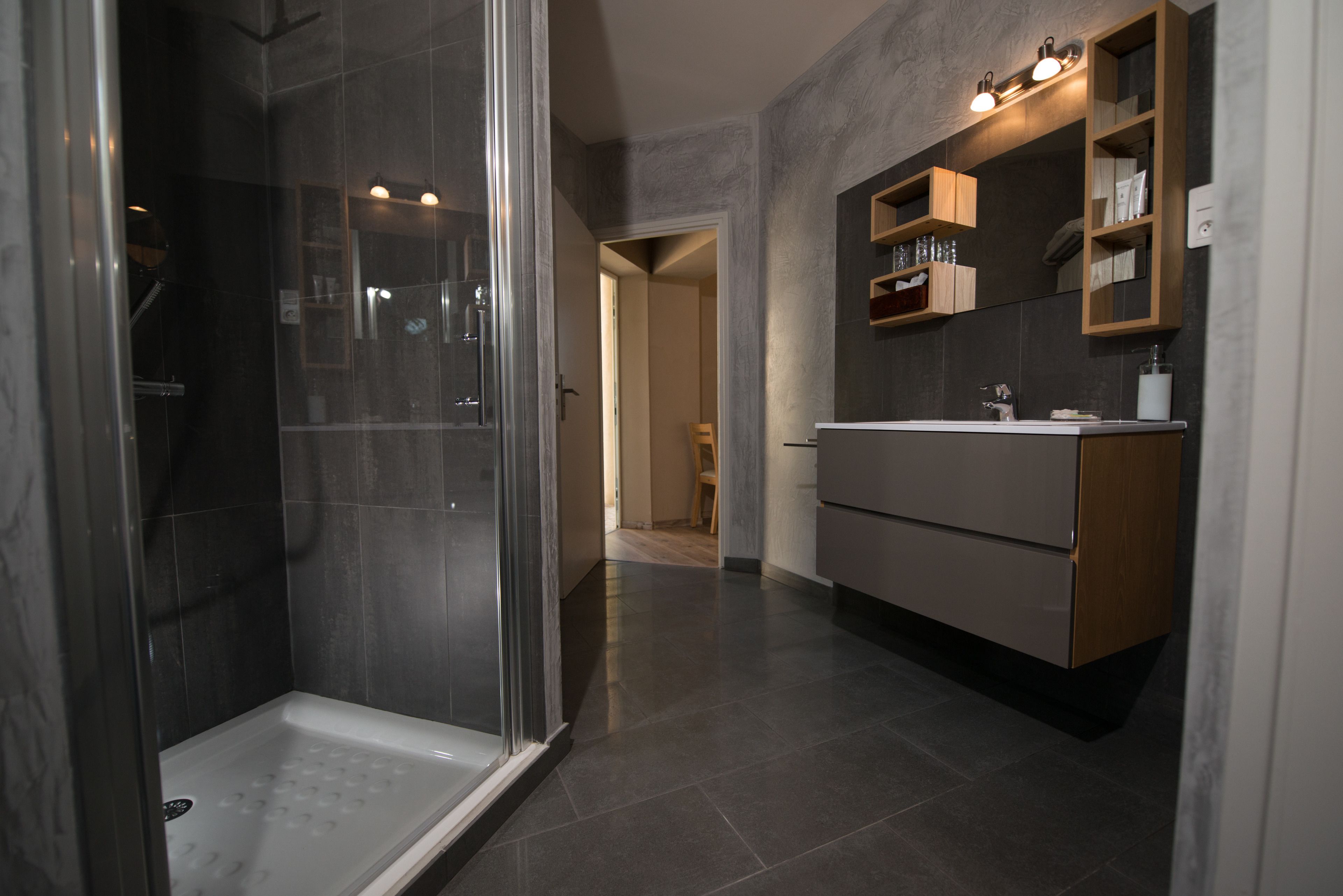 Een moderne badkamer met een douchecabine van glas, een wastafel met spiegel en een inloopkast.