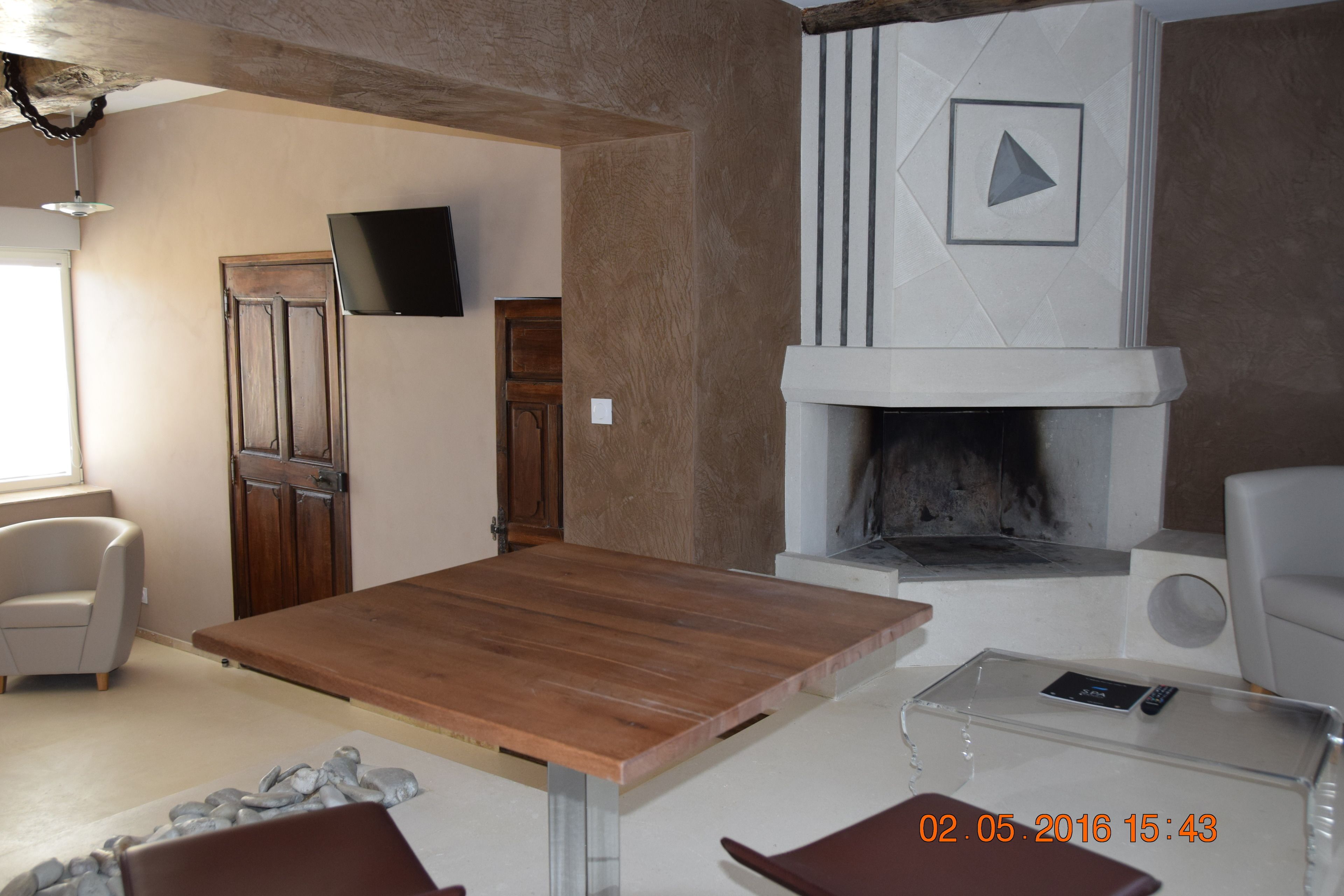 Un salon moderne avec une table en bois, une cheminée et un téléviseur à écran plat fixé au mur.