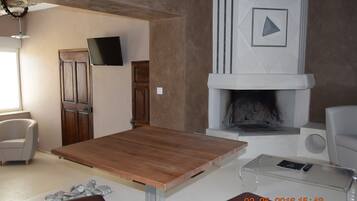 Un salon moderne avec une table en bois, une cheminée et un téléviseur à écran plat fixé au mur.