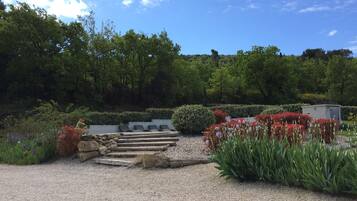 A garden with a gravel path, stone steps, and various plants and flowers.