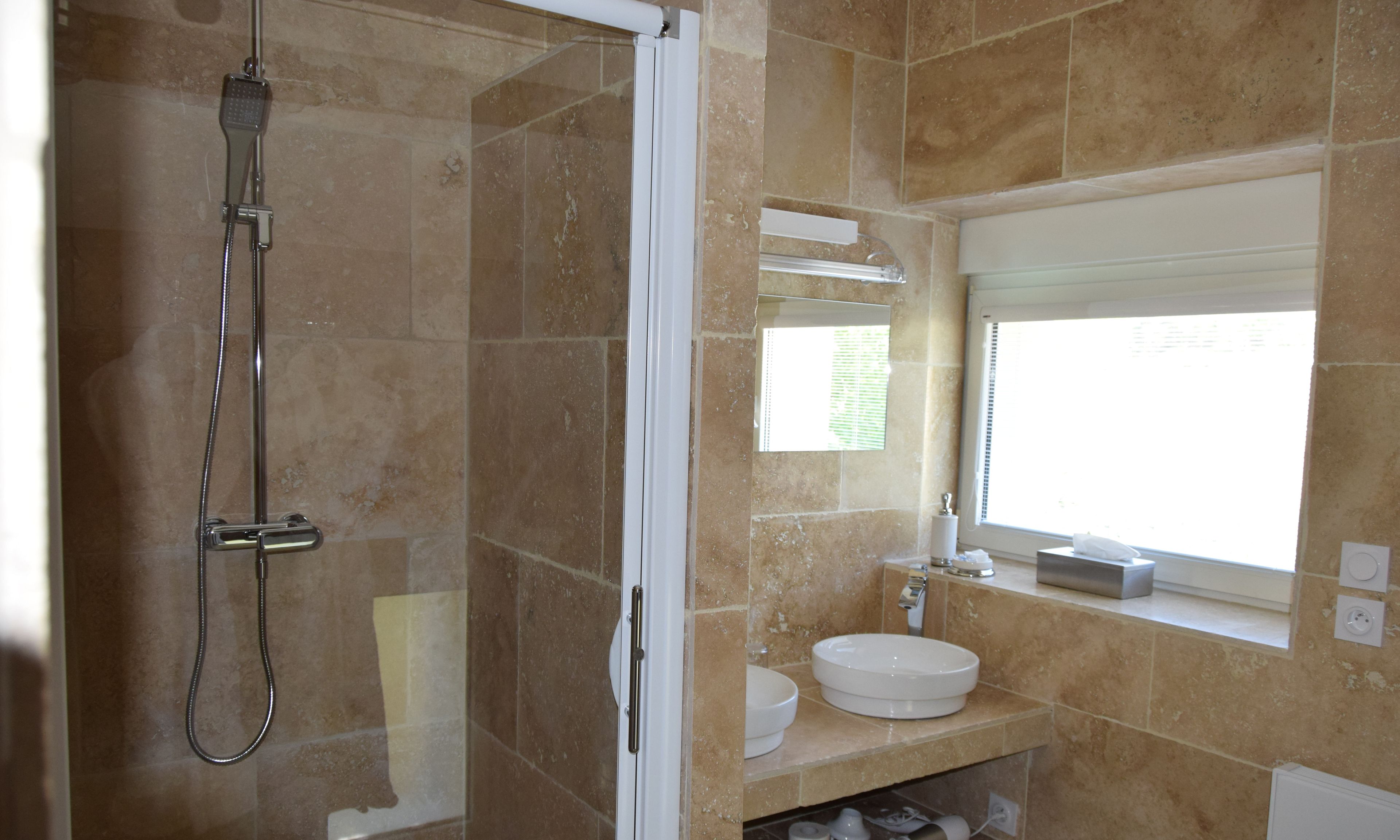 A bathroom with a shower, a sink, and a window.