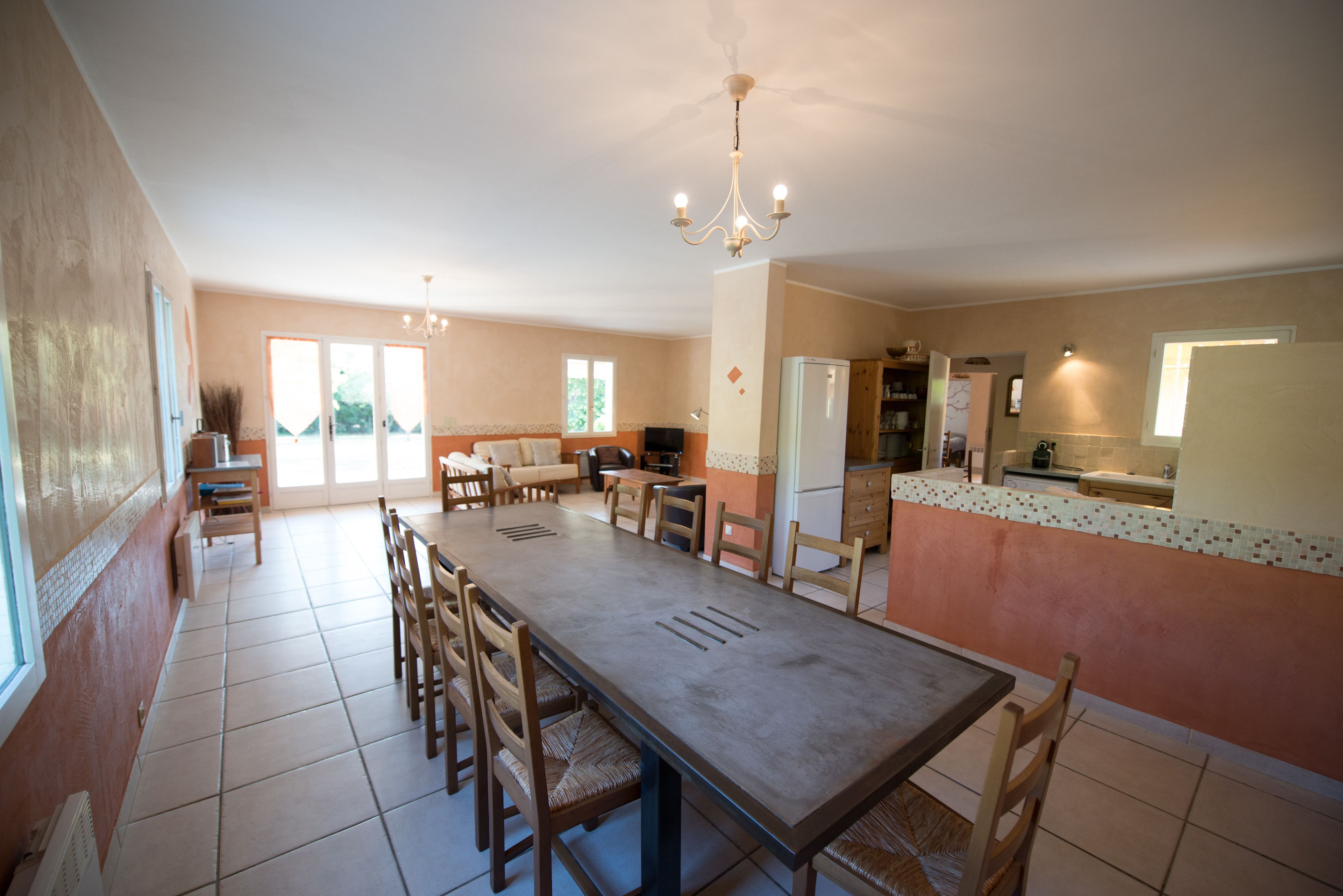 Une cuisine spacieuse avec une longue table à manger, des chaises et un lustre.