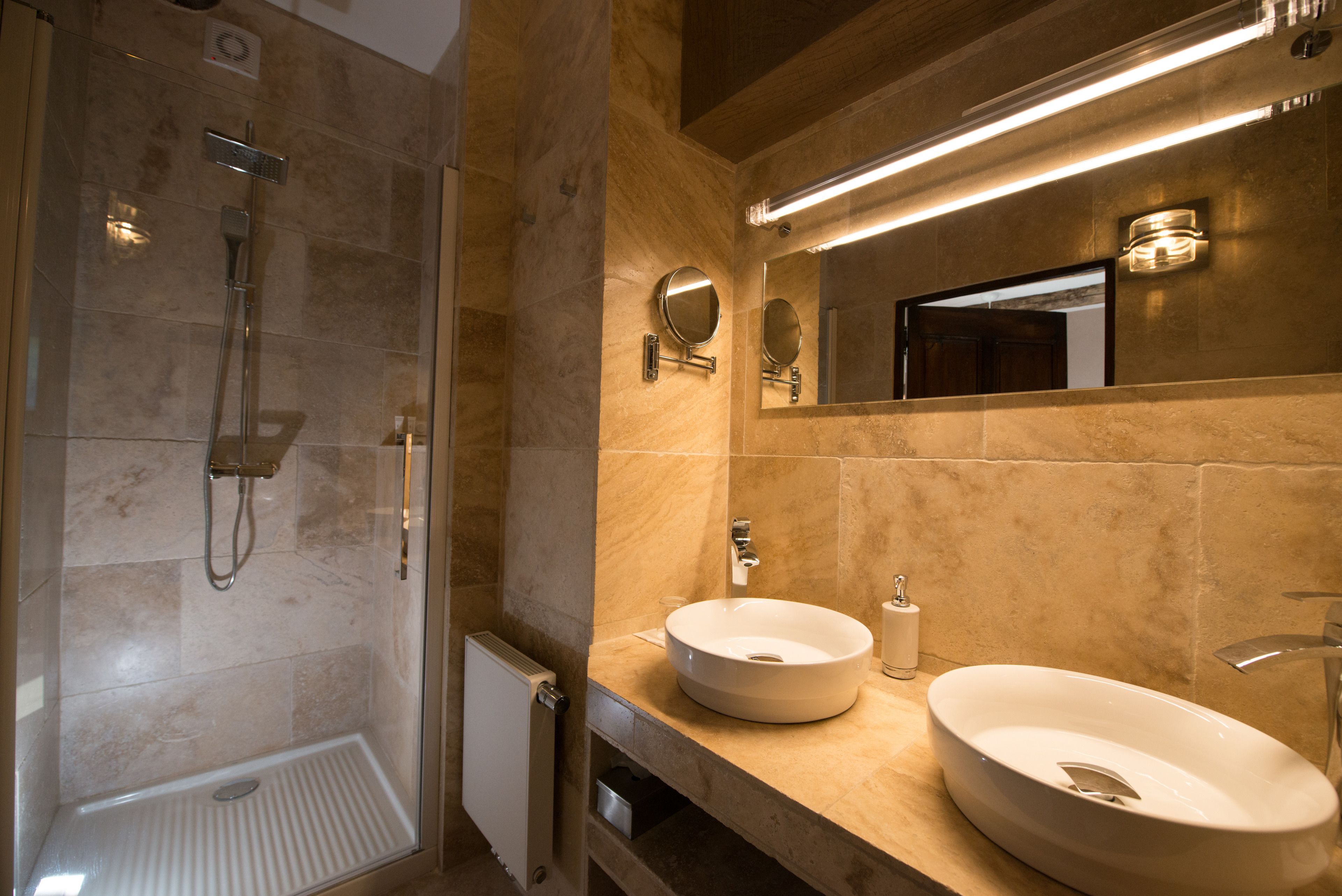 Een moderne badkamer met een inloopdouche, twee wastafels en een grote spiegel.