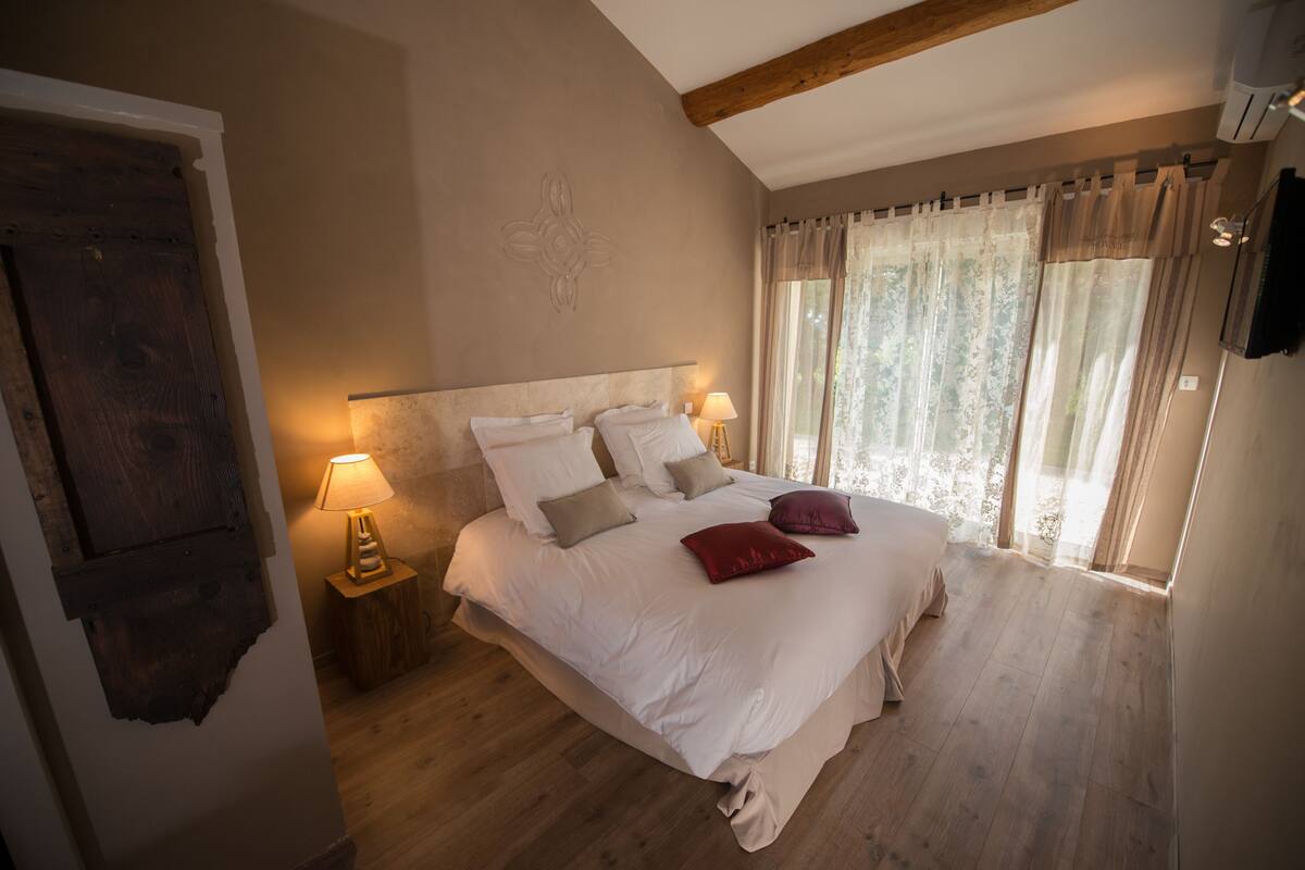 Ein Schlafzimmer mit einem großen Bett, Holzboden und einem Fenster mit Vorhängen.