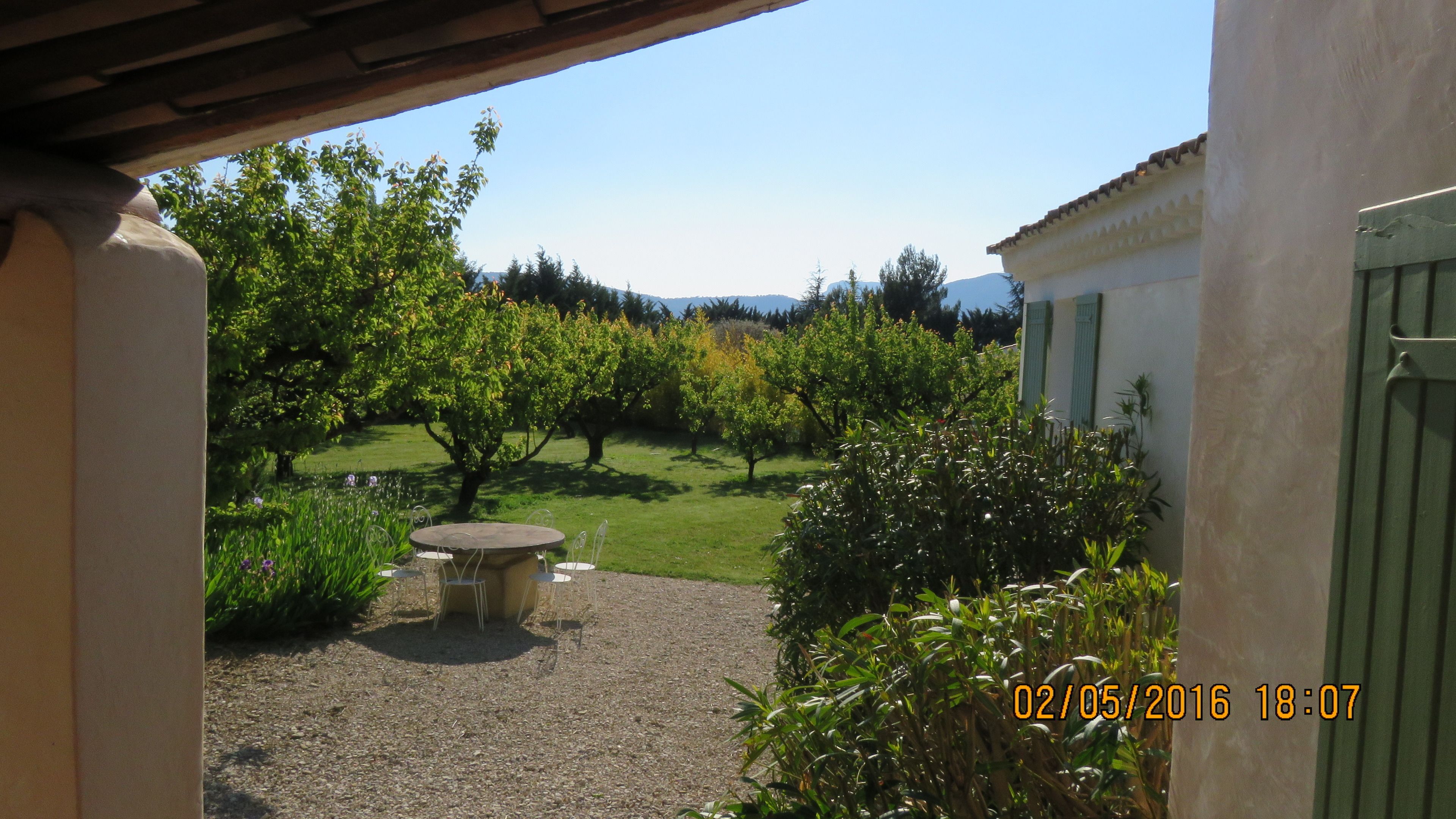 Un giardino con tavolo e sedie, un edificio con una porta verde e un timbro di data.