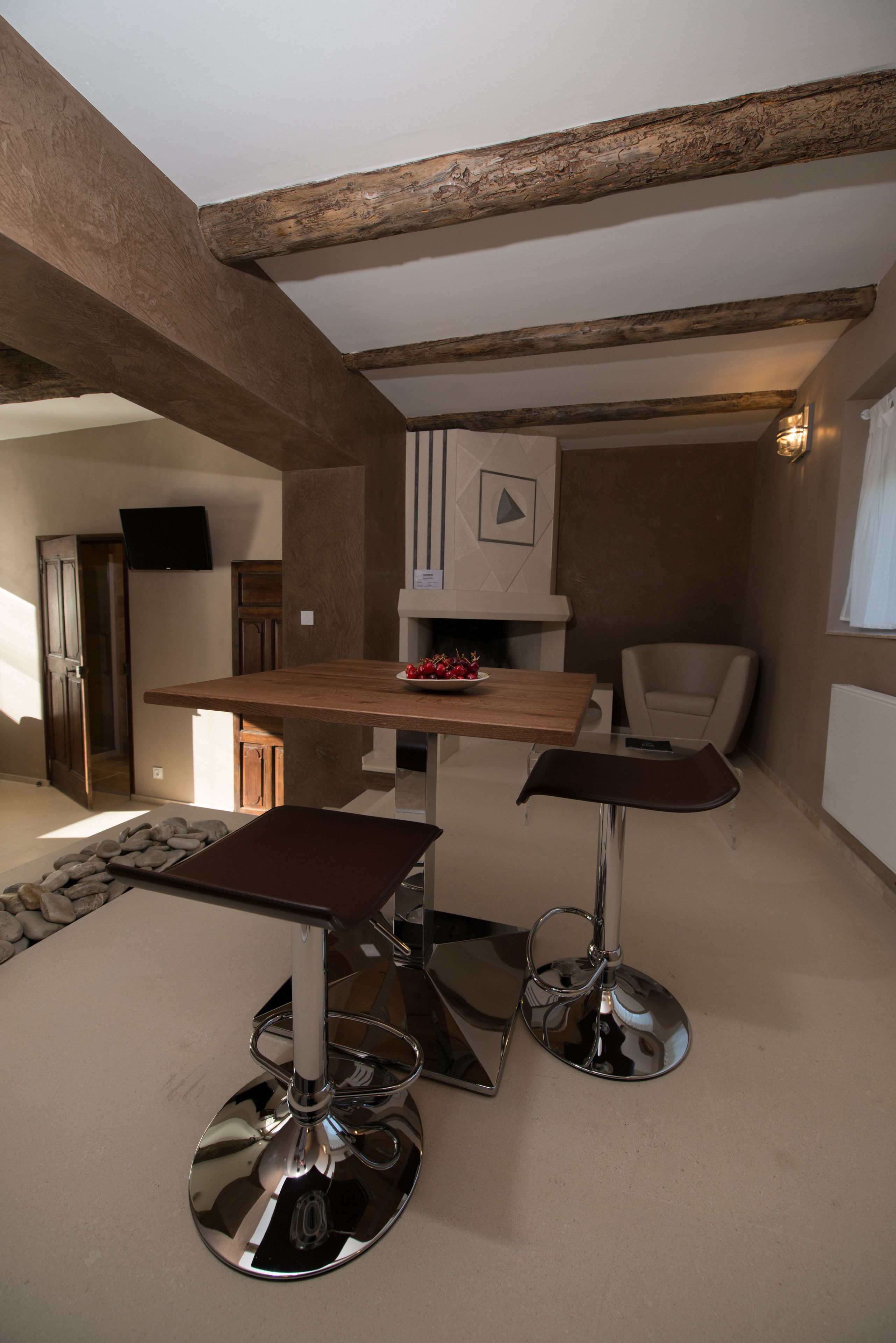 A modern kitchen with a wooden table, two bar stools, and a built-in TV.
