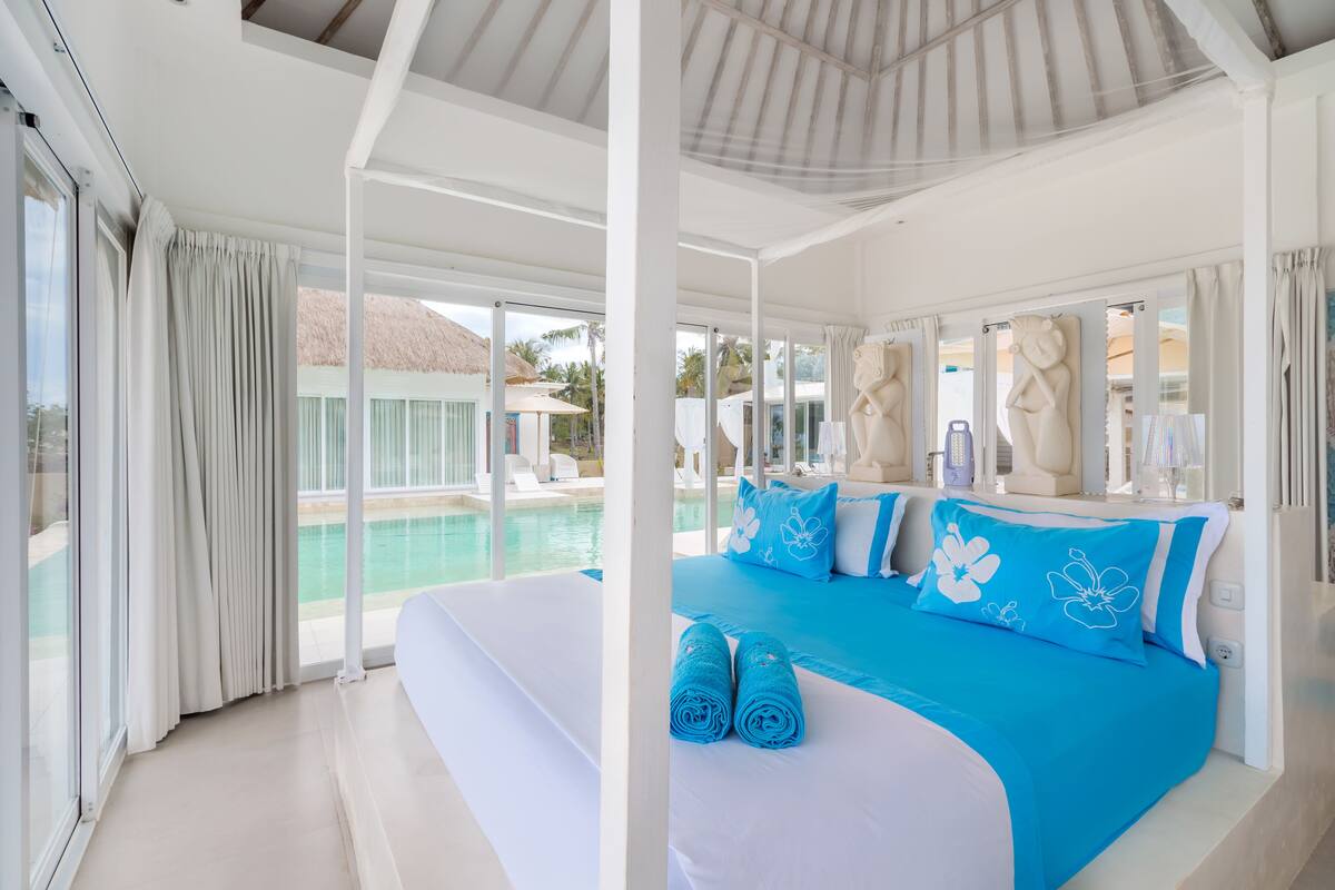 Una habitación de hotel moderna con una cama grande, vistas a una piscina y un balcón.