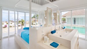 Une salle de bain moderne avec une grande baignoire, un meuble-lavabo avec un miroir et une vue sur la piscine.