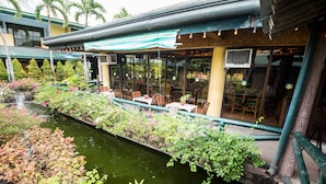 A restaurant with outdoor seating overlooking a water feature and lush greenery. - Family Country Hotel & Convention Center (General Santos)