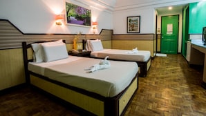 A hotel room with two beds, a wooden herringbone floor, and a green door. - Family Country Hotel & Convention Center (General Santos)