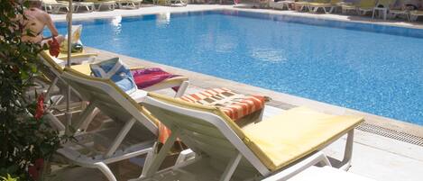 Een buitenzwembad, parasols bij het zwembad en ligstoelen