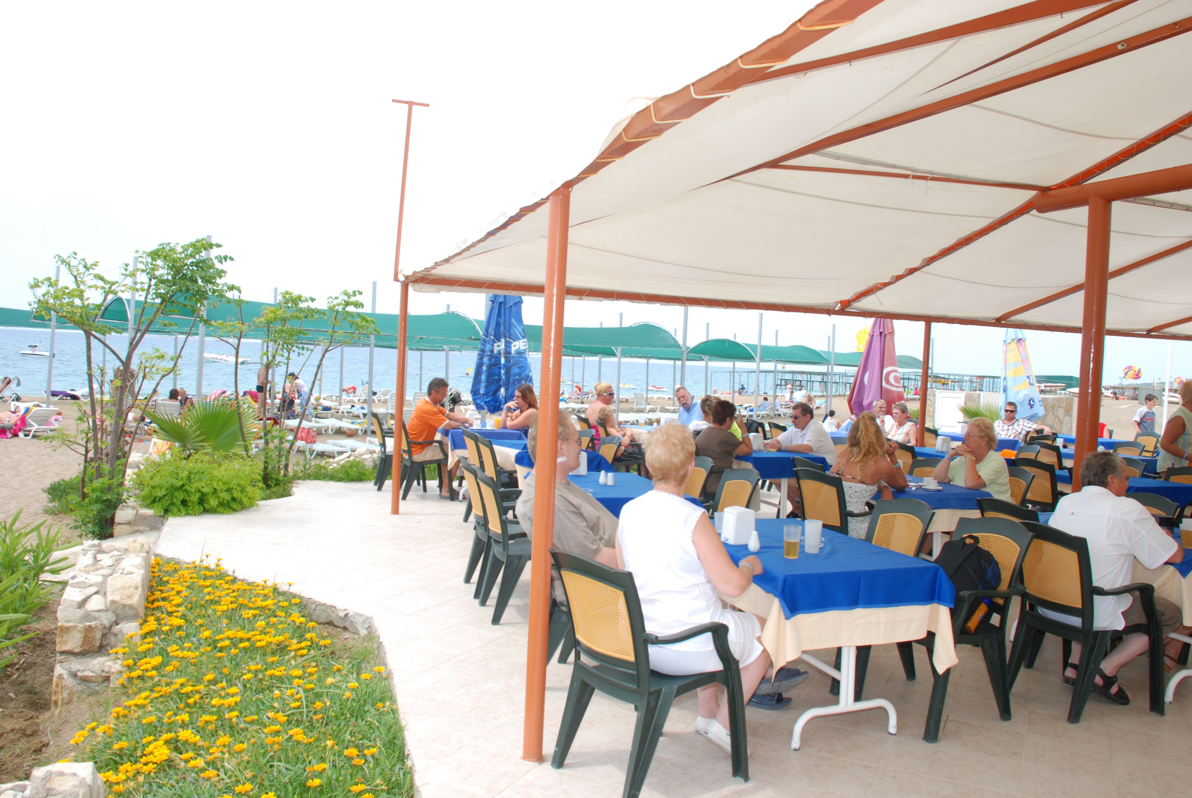 An outdoor dining area with tables and chairs, overlooking a body of water.