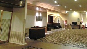 Un hall d’hôtel spacieux, doté d’un plafond haut, d’un éclairage encastré et d’un tapis à motifs.