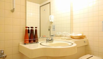 Un baño con lavamanos, espejo y artículos de aseo.