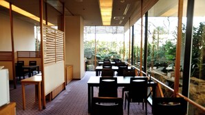 Un restaurant offrant une vue sur la verdure grâce à de grandes fenêtres, doté de meubles en bois et d’un sol à motifs.