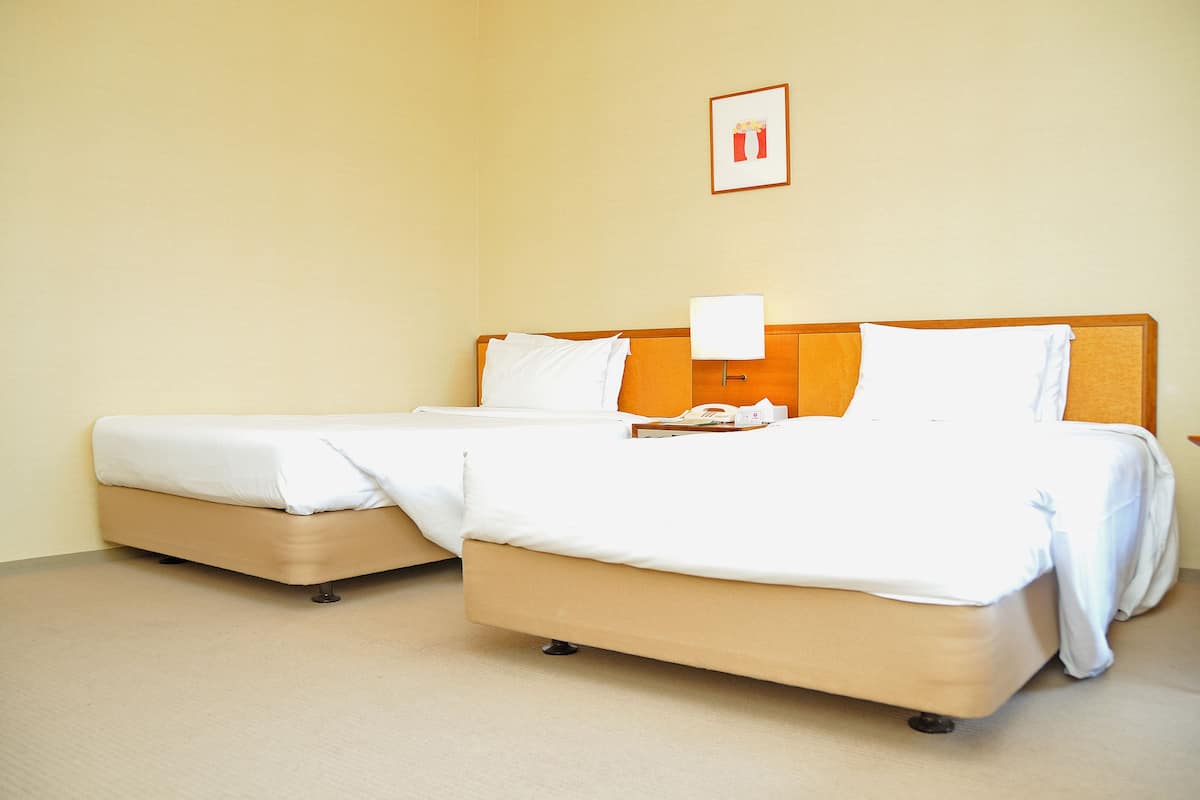 Ein Hotelzimmer mit zwei Betten, einem Nachttisch und einem gerahmten Bild an der Wand.
