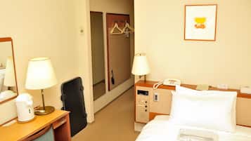 A hotel room with a bed, two bedside lamps, a desk with a lamp, a coffee maker, a telephone, and a coat rack with hangers.