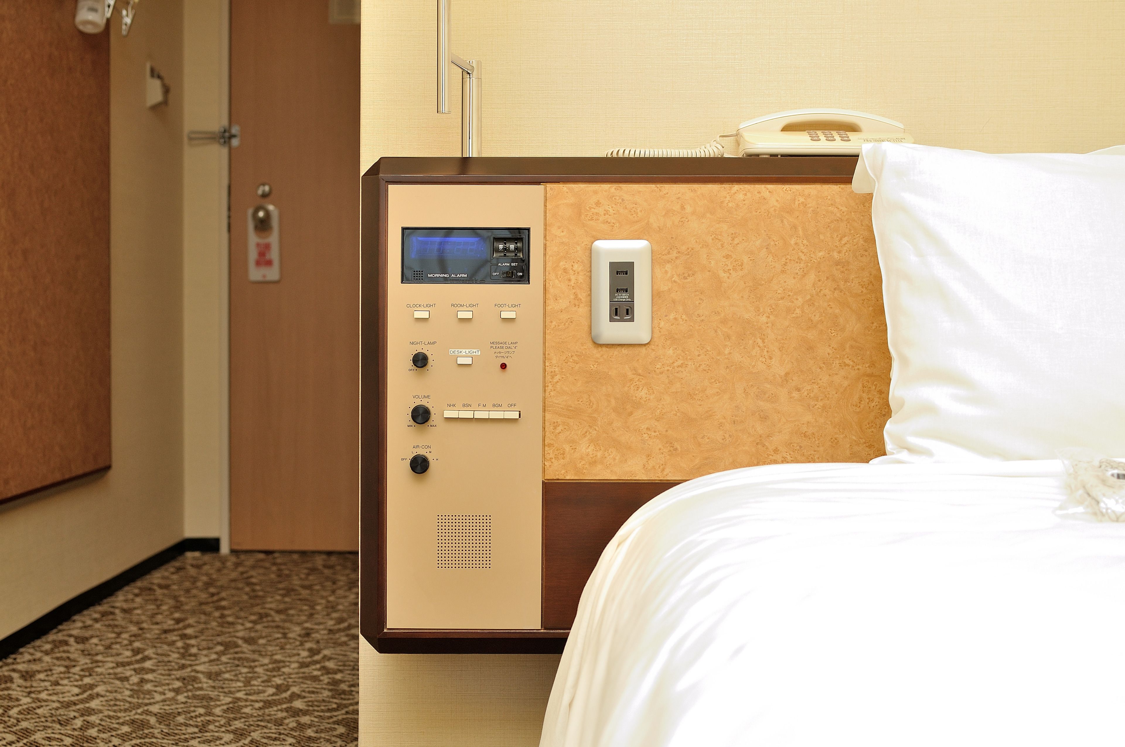 Habitación de hotel con panel de control para la iluminación y un teléfono.