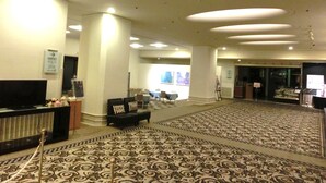 A spacious lobby with a patterned carpet, a reception desk, and a television. - Hotel New Otani Nagaoka (Nagaoka)