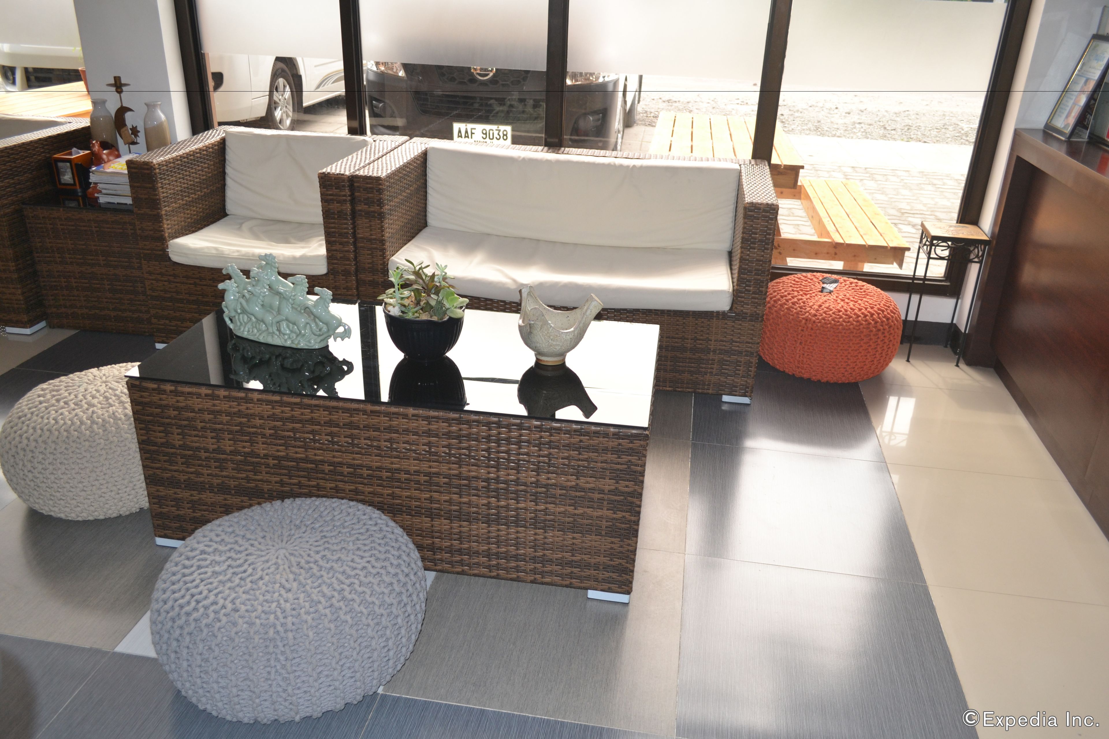 Un espacio al aire libre moderno con mobiliario de mimbre, una mesa de centro de vidrio y elementos decorativos.