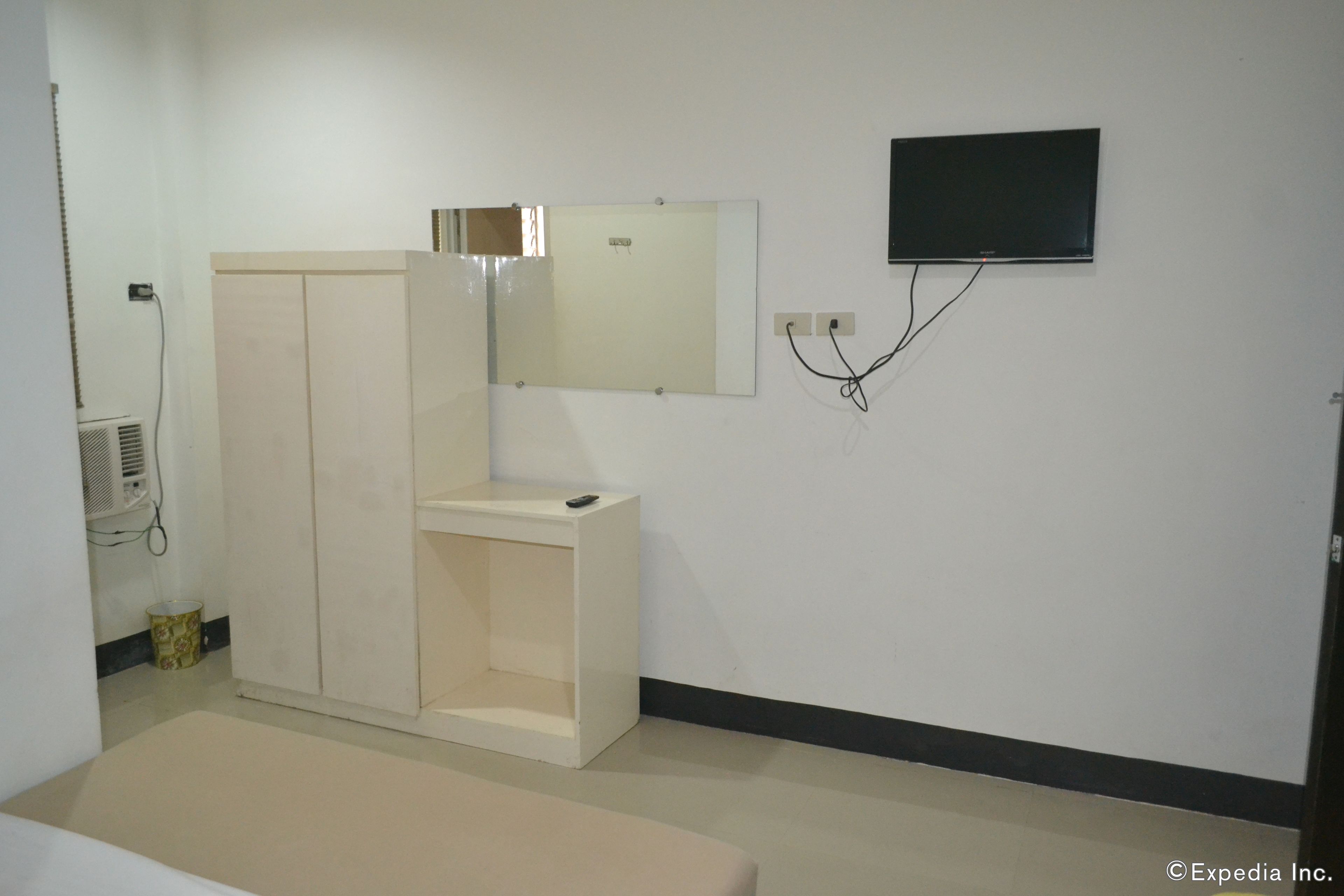 A room with a bed, a wardrobe, a mirror, a television, and a small table.
