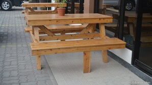 A wooden picnic table with benches, a potted plant, and a car parked in the background. - Pearl Suites (General Santos)