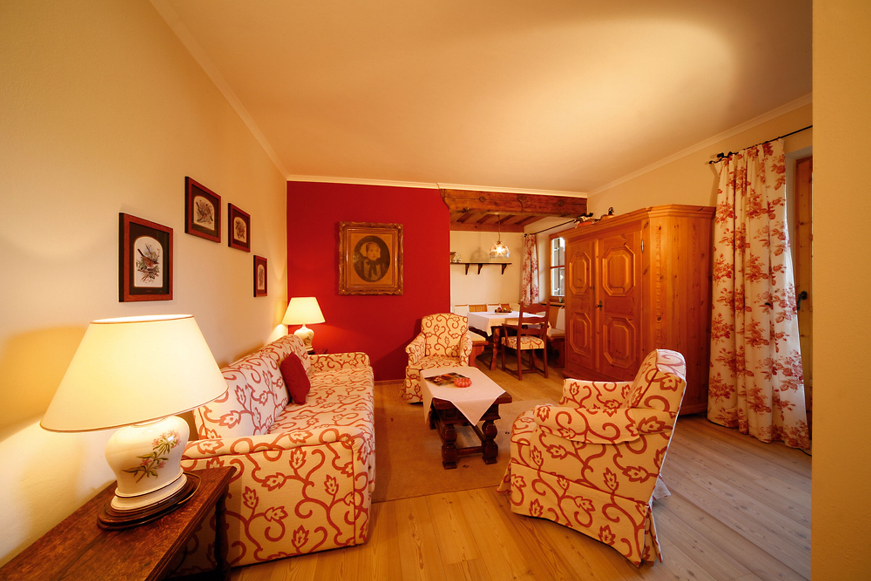 A cozy living room with patterned furniture, a dining area, and a wooden cabinet.