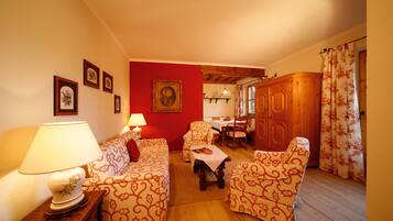 A cozy living room with patterned furniture, a dining area, and a wooden cabinet.