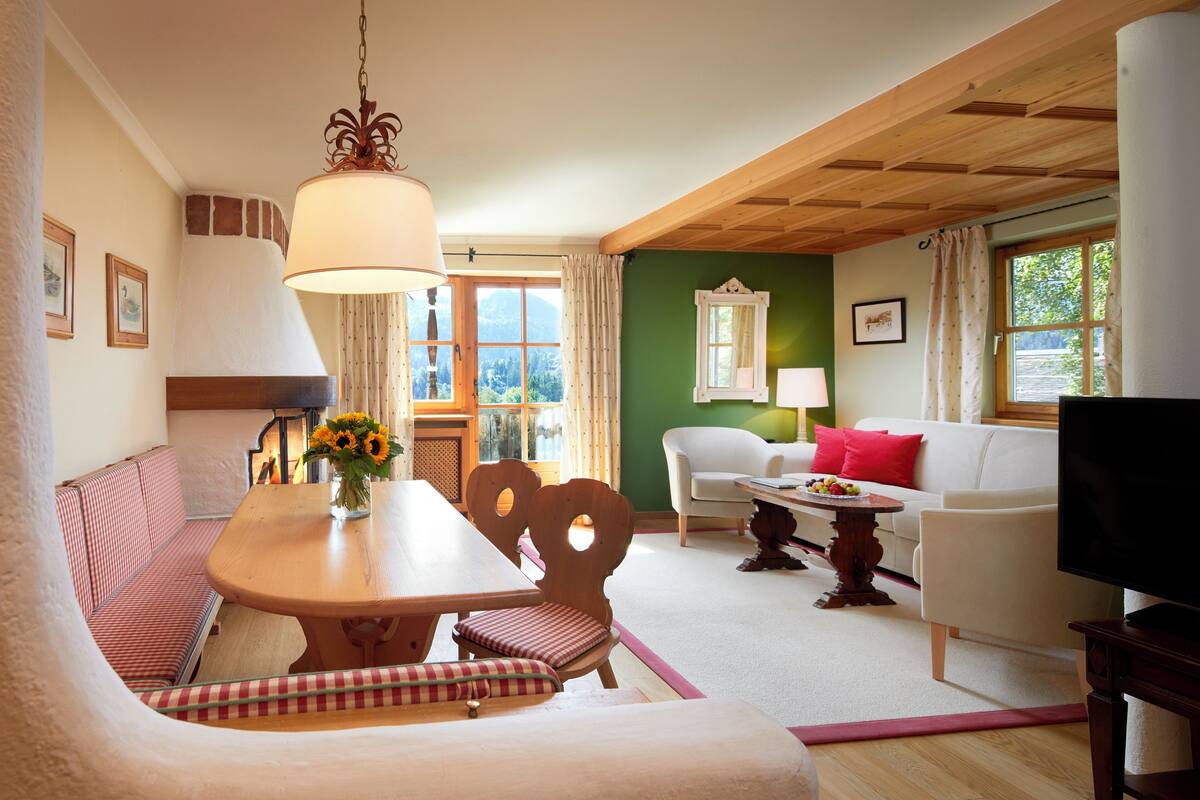 A cozy living room with a wooden dining table, a sofa, and a television.