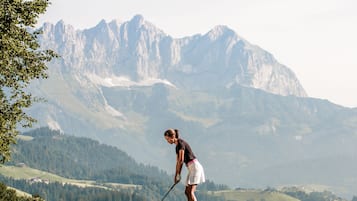 Un camp de golf amb un paisatge de muntanyes al fons.