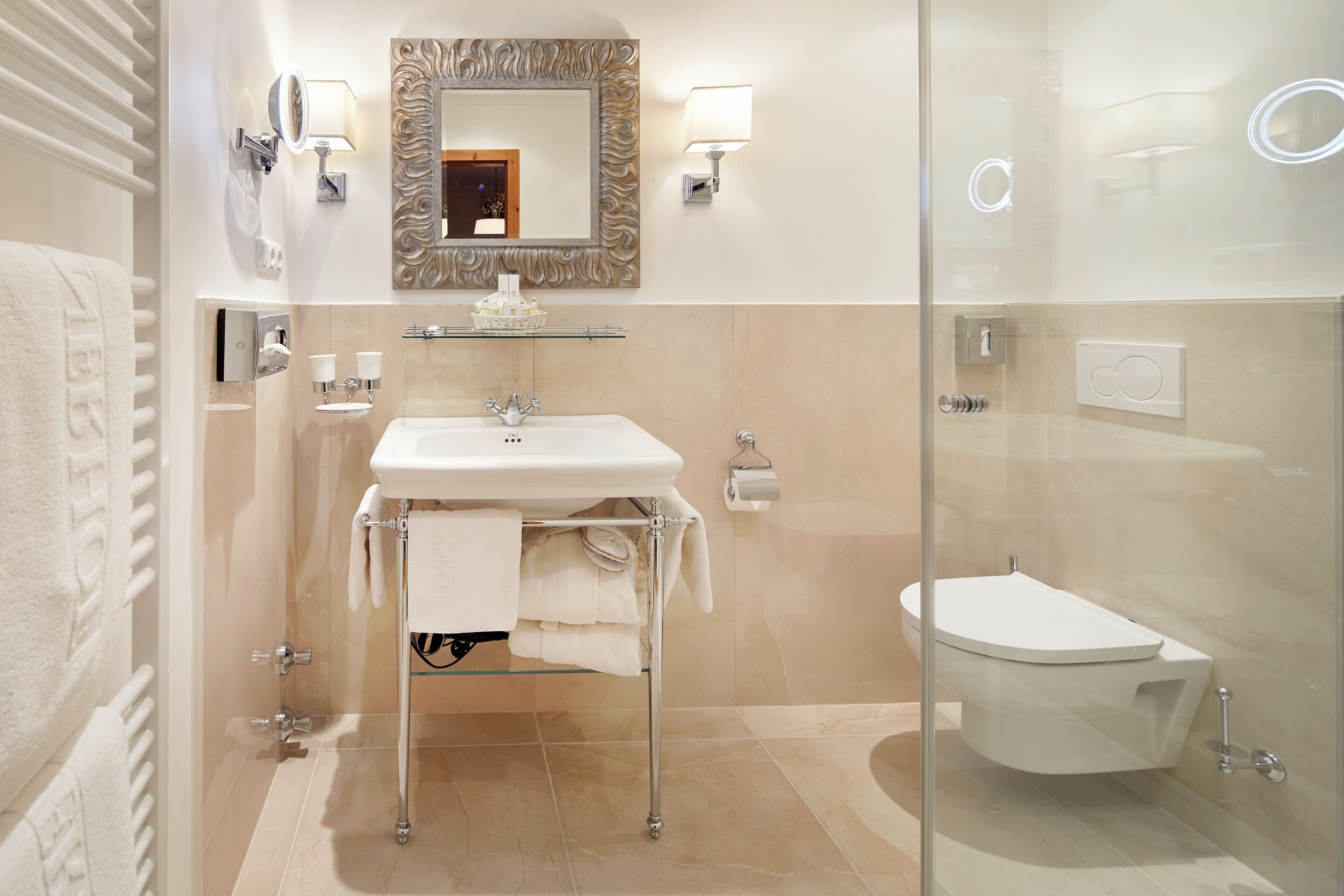 Ein modernes Badezimmer mit einer Duschkabine aus Glas, einem weißen Waschbecken und einem großen Spiegel mit Zierrahmen.