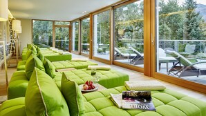 A modern living room with green sofas, a magazine, and a glass table with fruit and drinks. - Landsitz Römerhof - Hotel Apartments (Kitzbuhel)