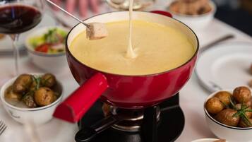 A fondue pot on a table with various dipping items and a wine glass.