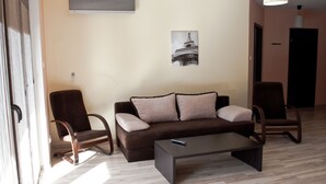 A living room with a brown sofa, two armchairs, a coffee table, and a painting of the Eiffel Tower. - Baltic Sol (Wladyslawowo)