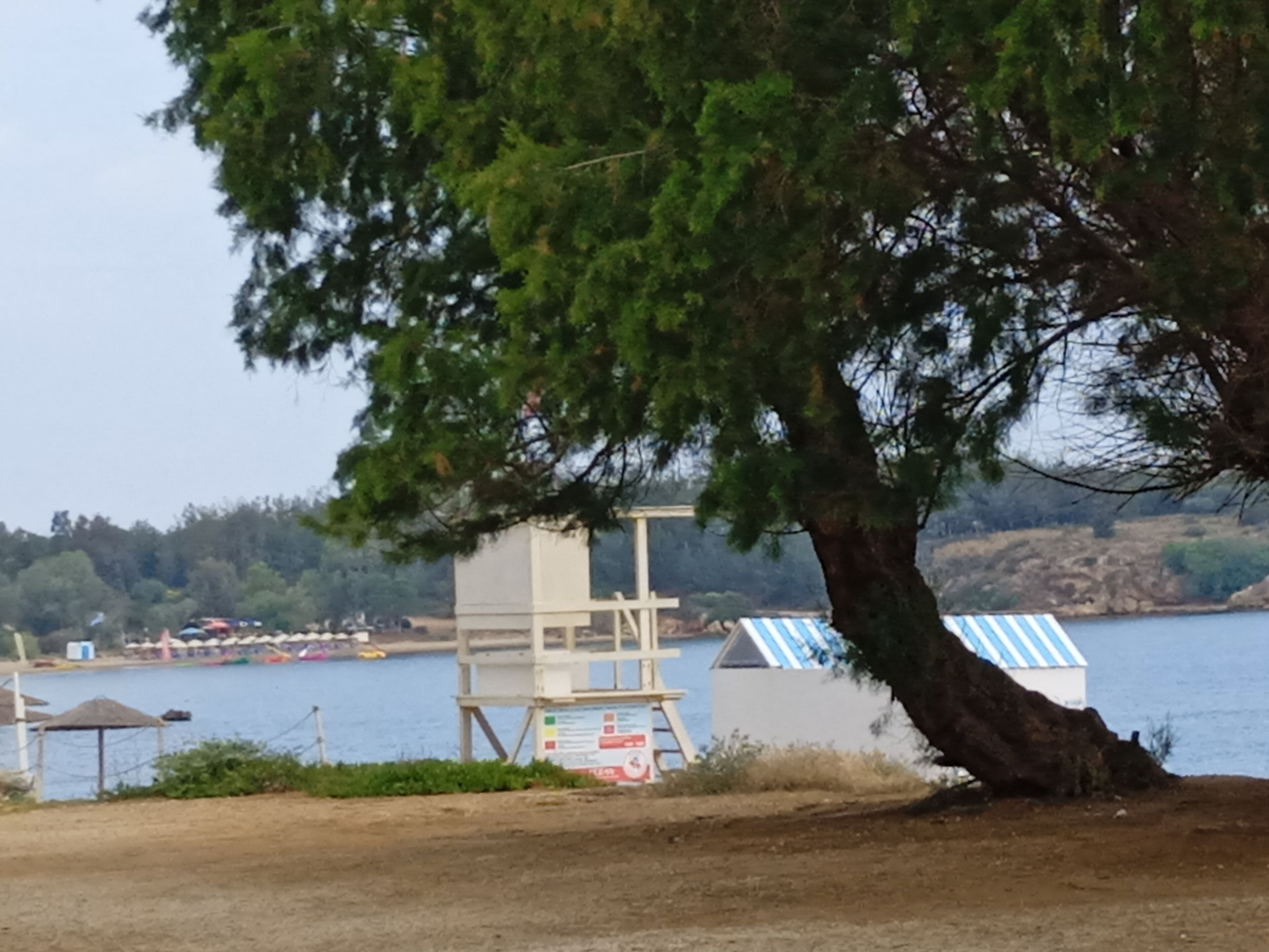 A coastal area with a lifeguard tower, beach huts, and a body of water.