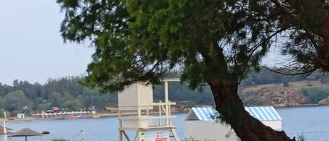 A coastal area with a lifeguard tower, beach huts, and a body of water.