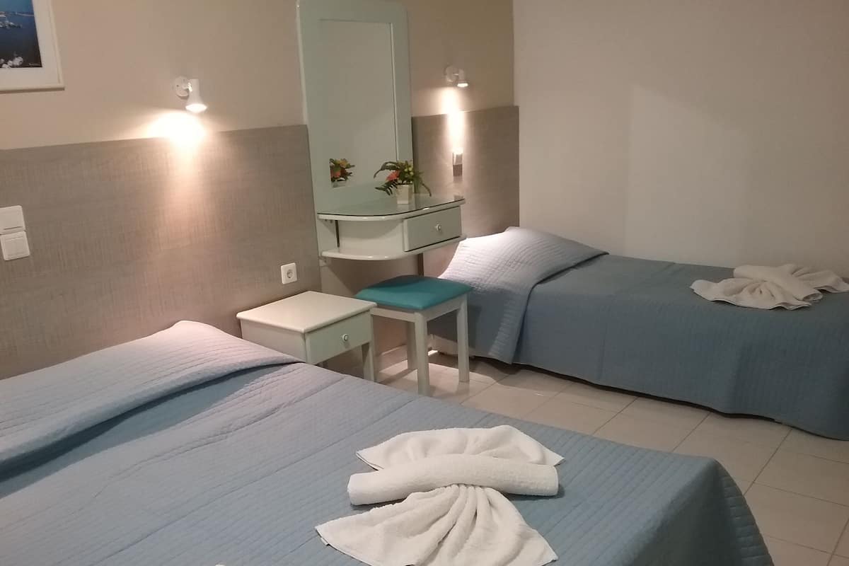 A hotel room with two beds, a small desk, a mirror, and a nightstand.