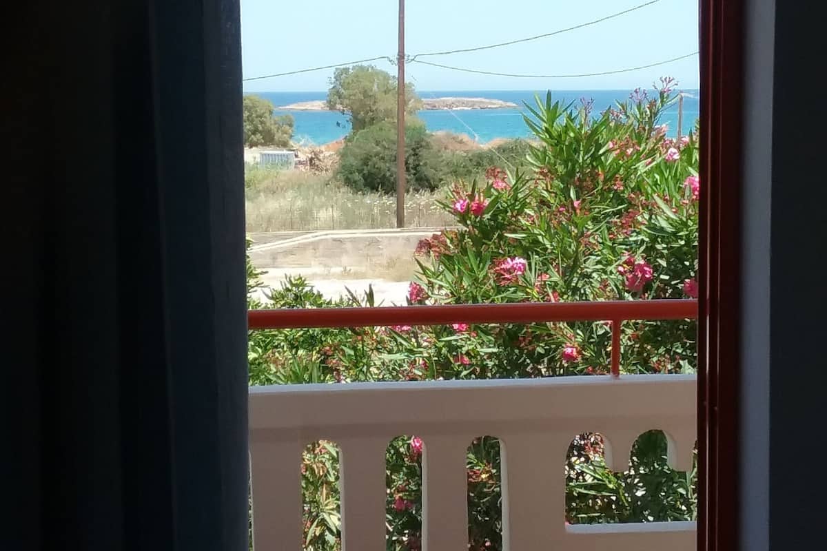 A balcony with a view of a coastal landscape, including a beach and a clear sky.