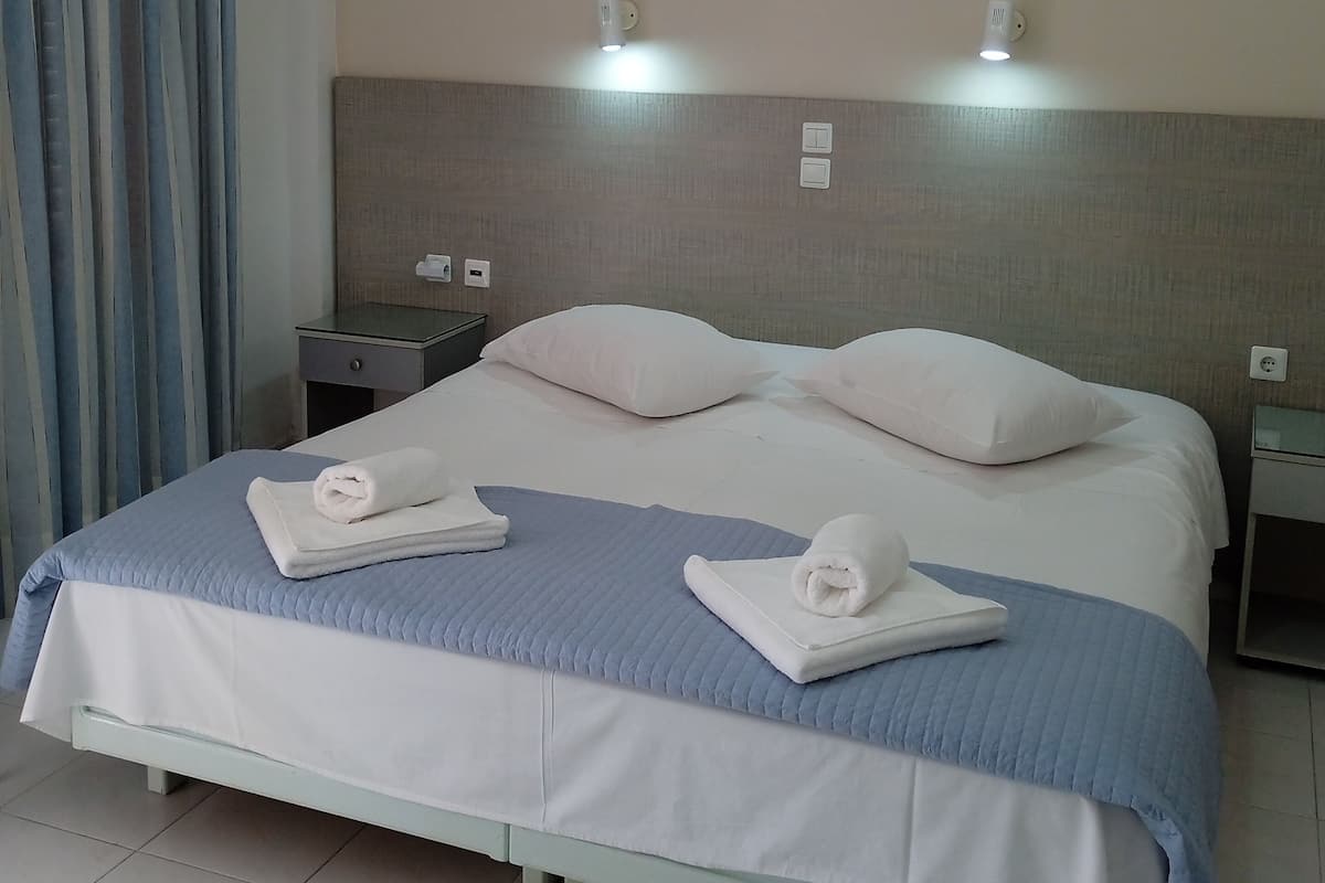 A neatly made bed with white and blue bedding, two bedside lamps, and a nightstand with a lamp.