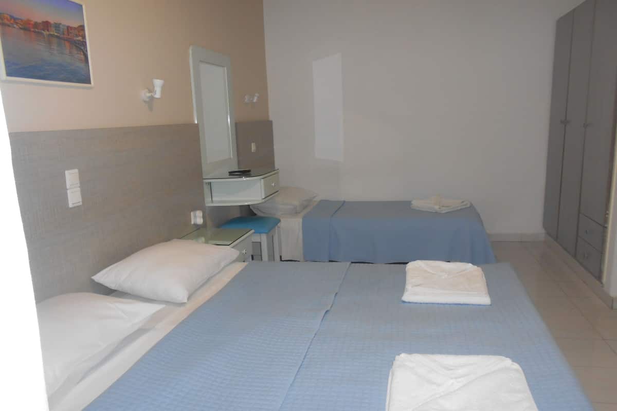 A hotel room with two beds, a desk, a chair, a mirror, and a wardrobe.