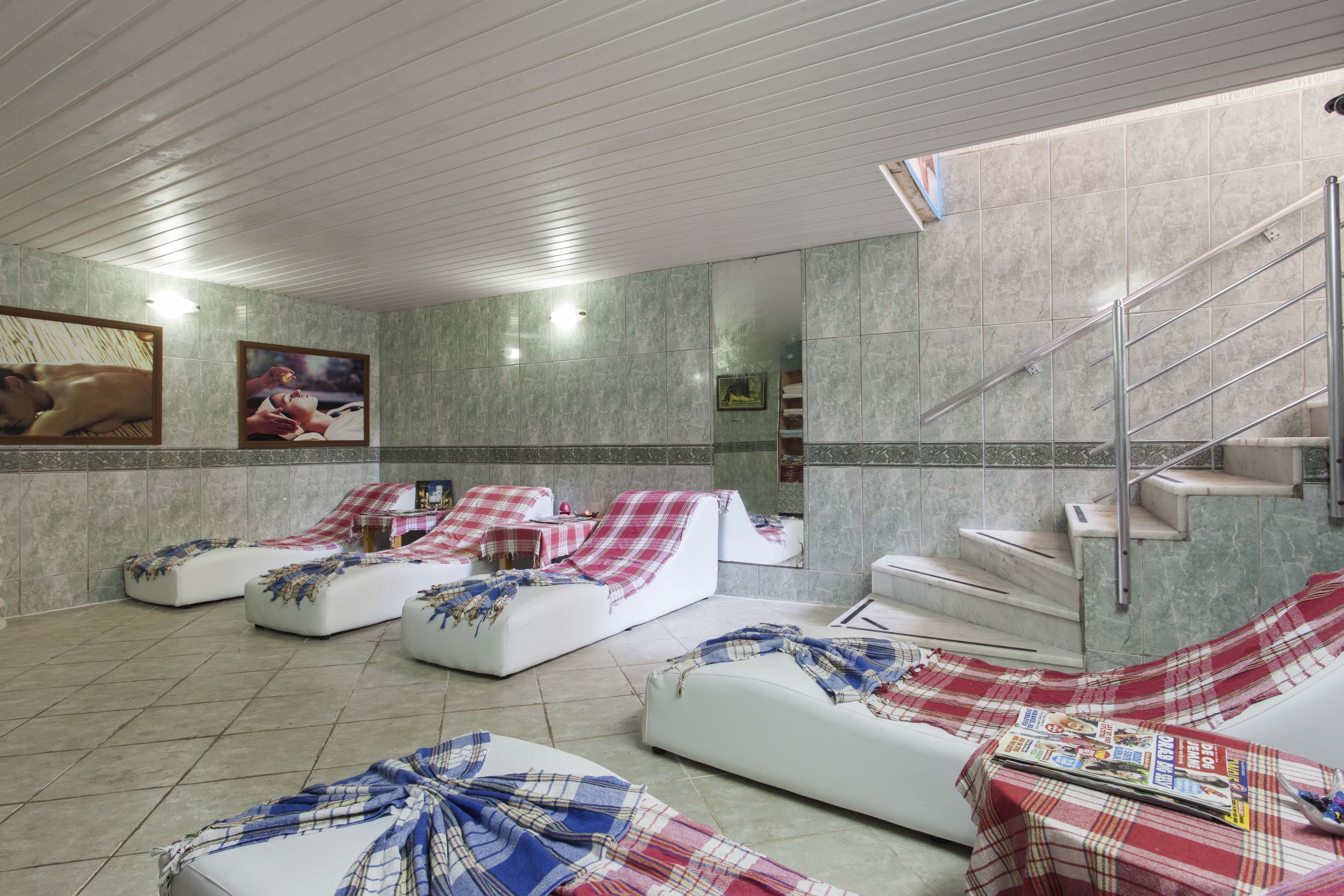 A spa area with reclining chairs, a staircase, and a tiled wall.