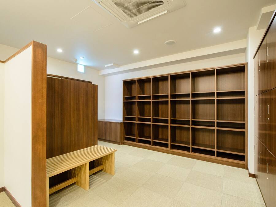 A room with a wooden bench, a large wardrobe, and a built-in shelving unit.