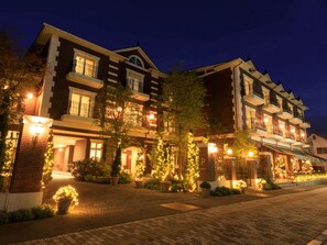 A multi-story hotel with a brick facade, multiple balconies, and outdoor lighting. - Le Grand Kyu Karuizawa (Karuizawa)
