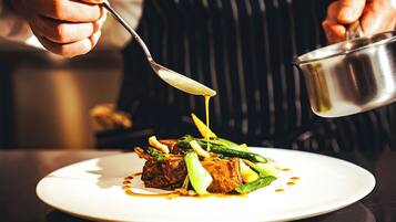 A person pouring sauce over a plated dish.