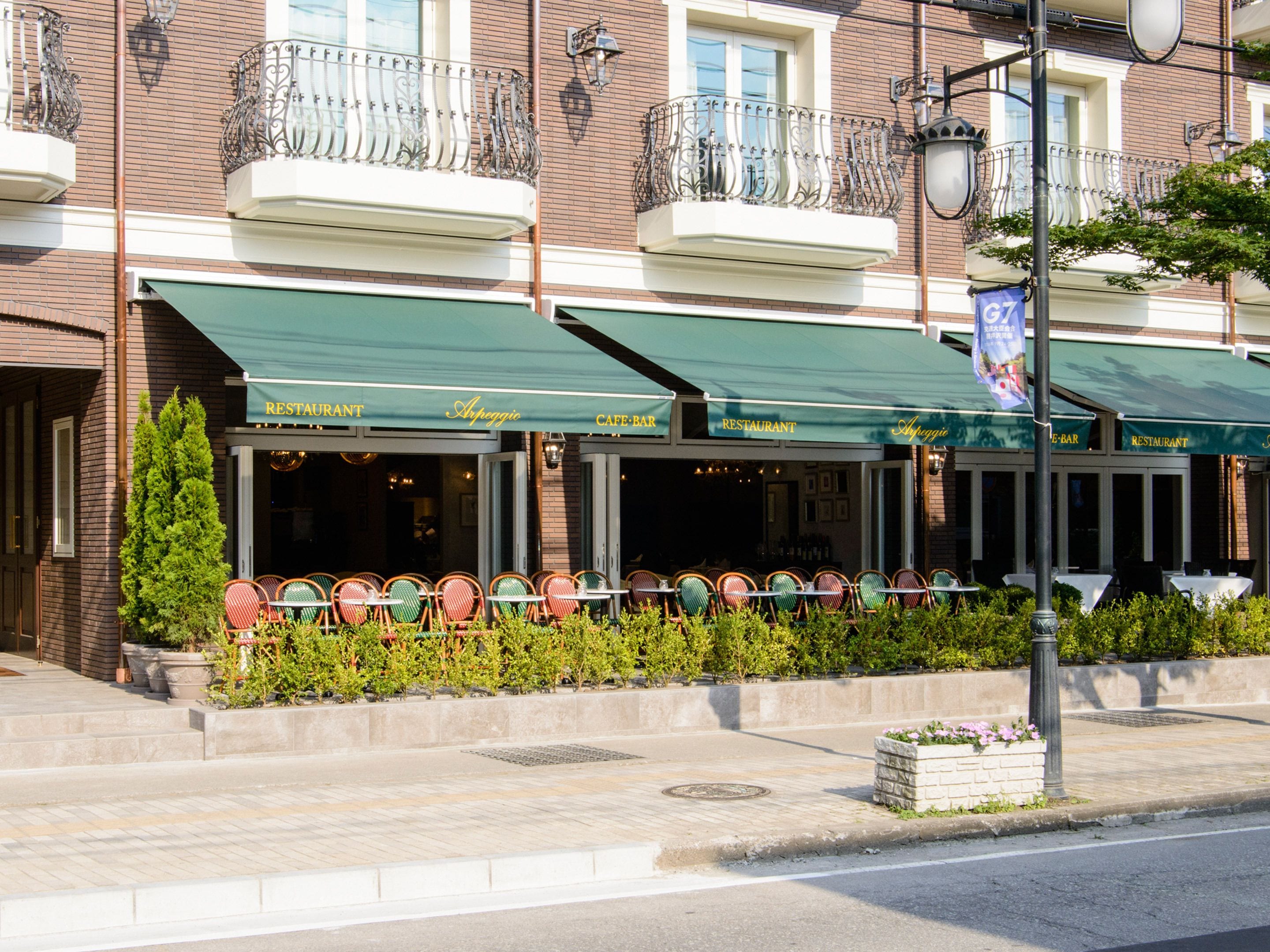 Ein Restaurant mit Außenbereich, einer Ziegel-Fassade und einem grünen Markisenvorbau.