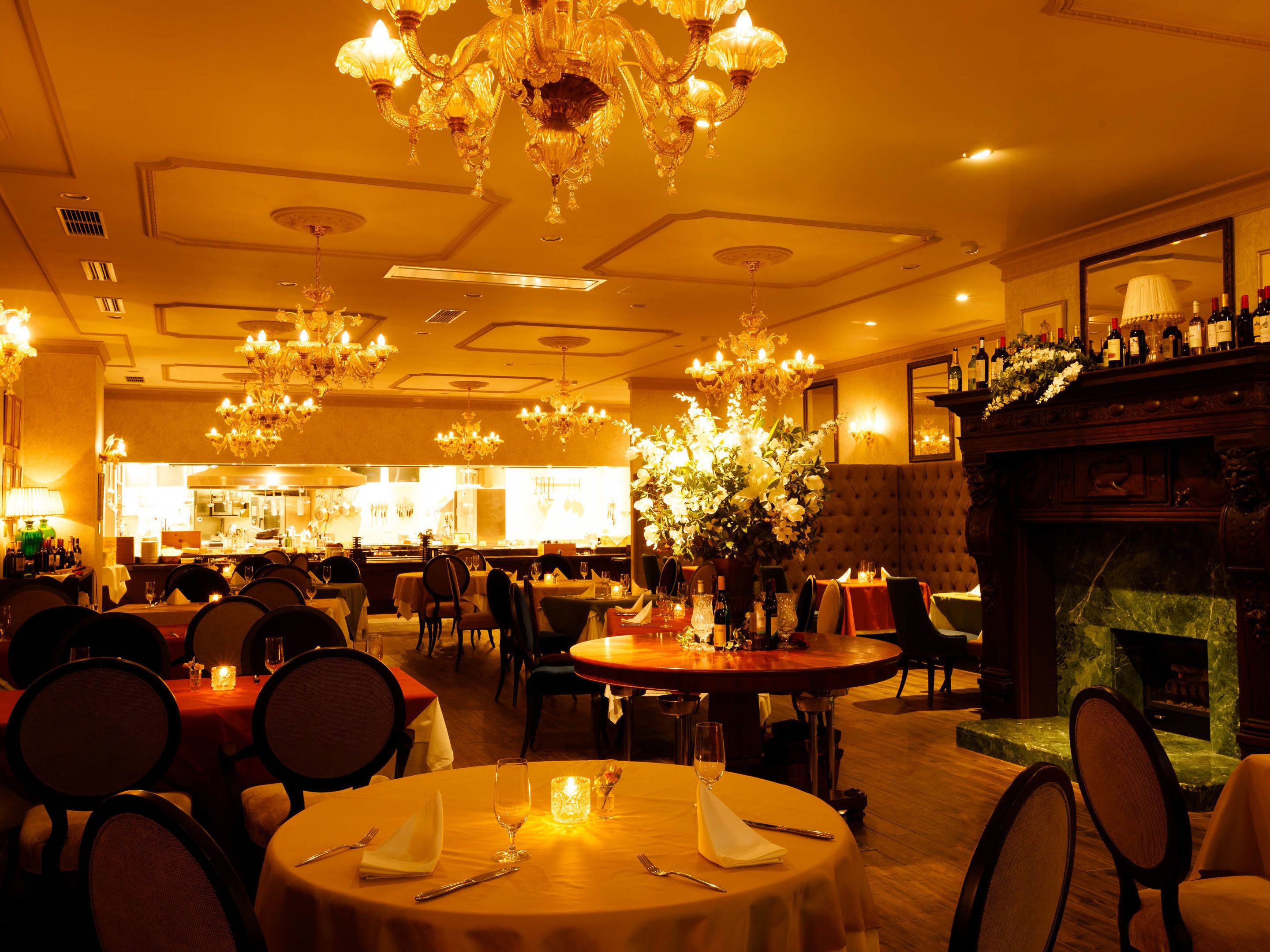 Un restaurant avec des tables rondes, des lustres et une cheminée.