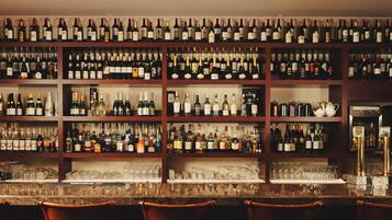 Una zona de bar con varias estanterías llenas de botellas de vino y copas.